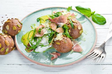 Proshutto, yumurta ve arugula ile sandviç. Kahvaltı. Tabakta. Üst te. Düz döşeme kompozisyonU Ücretsiz kopyalama alanı.