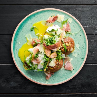 Proshutto, yumurta ve arugula ile sandviç. Kahvaltı. Tabakta. Üst te. Düz döşeme kompozisyonU Ücretsiz kopyalama alanı.