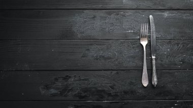 Karanlık bir arka plan üzerinde eski çatal bıçak takımı. Üst te. Ücretsiz kopyalama alanı.