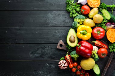 Siyah bir arka plan üzerinde taze sebze. Avokado, domates, patates, kırmızı biber, narenciye. Üst te. Metniniz için boş alan.