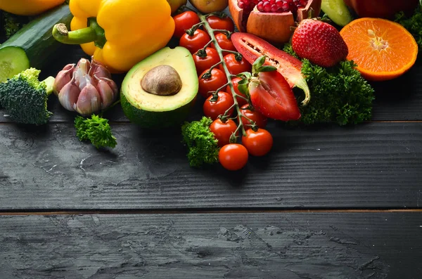 Fresh vegetables on a black background. Avocados, tomatoes, potatoes, paprika, citrus. Top view. Free space for your text.