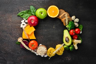 Doğal karbonhidratlı gıdalar: ekmek, makarna, avokado, un, kabak, brokoli, fasulye, ıspanak. Kahverengi bir arka plan üzerinde. Üst te. Ücretsiz kopyalama alanı.