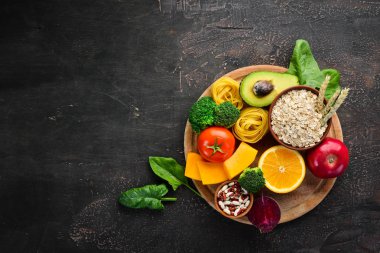 Doğal karbonhidratlı gıdalar: ekmek, makarna, avokado, un, kabak, brokoli, fasulye, ıspanak. Kahverengi bir arka plan üzerinde. Üst te. Ücretsiz kopyalama alanı.