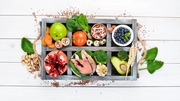 Healthy food for the heart: Fish, blueberries, nuts, pomegranate, avocados, tomatoes, spinach, flax. On a white wooden background. Top view.