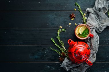 Kırmızı bir fincan ve çaydanlıkyeşil çay. Üst te. Metniniz için boş alan. Siyah arka planda.