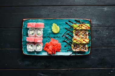 Suşi ve tabakta rulo. Üst te. Metniniz için boş alan. Siyah arka planda.