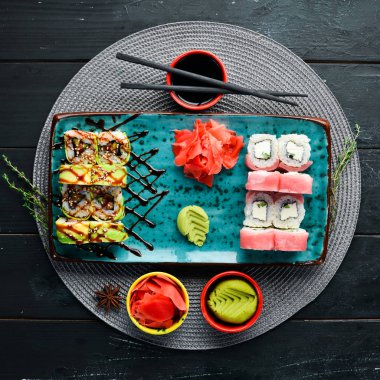 Suşi ve tabakta rulo. Üst te. Metniniz için boş alan. Siyah arka planda.