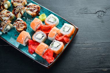 Suşi ve tabakta rulo. Üst te. Metniniz için boş alan. Siyah arka planda.