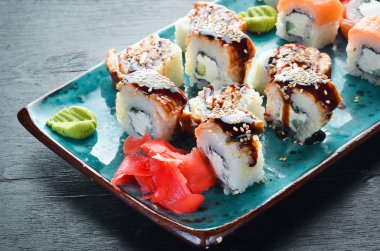 Suşi ve tabakta rulo. Üst te. Metniniz için boş alan. Siyah arka planda.