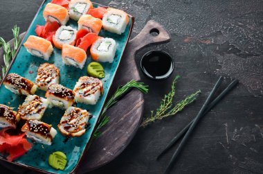 Suşi ve tabakta rulo. Üst te. Metniniz için boş alan. Siyah arka planda.