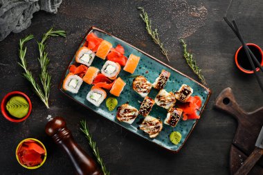 Bir tabakta suşi ve rulo varyasyonu. Üst te. Metniniz için boş alan. Karanlık bir arka plan üzerinde.