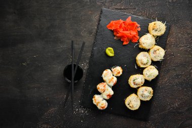 Bir tabakta suşi ve rulo varyasyonu. Üst te. Metniniz için boş alan. Karanlık bir arka plan üzerinde.