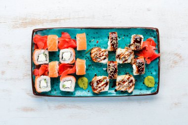 Suşi ve maki bir tabakta yuvarlanır. Üst te. Metniniz için boş alan. Beyaz arka planda.