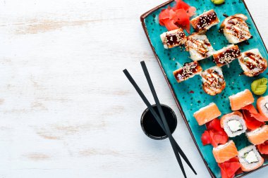 Suşi ve maki bir tabakta yuvarlanır. Üst te. Metniniz için boş alan. Beyaz arka planda.