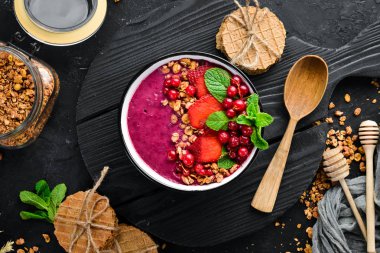 Granola, çilek, kırmızı kuş üzümü ve nane ile Smoothie kase. Kahvaltı. Üst te. Metniniz için boş alan.