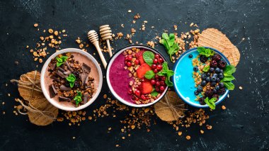 Yoğurt, taze meyve ve çilek ile renkli meyve smoothies büyük bir set. Sağlıklı bir kahvaltı. Üst te. Metniniz için boş alan. Siyah arka planda.