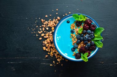 Mavi Spirulina ve Taze Meyve Smoothie Bowl böğürtlen, yaban mersini, granola ve yoğurt ile tepesinde. Kahvaltı. Üst te. Metniniz için boş alan.