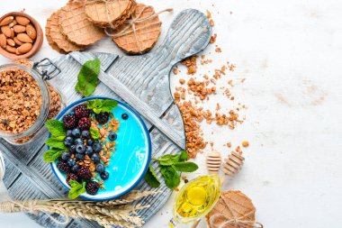 Mavi Spirulina ve Taze Meyve Smoothie Bowl böğürtlen, yaban mersini, granola ve yoğurt ile tepesinde. Kahvaltı. Üst te. Metniniz için boş alan.