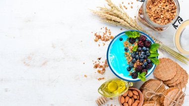 Mavi Spirulina ve Taze Meyve Smoothie Bowl böğürtlen, yaban mersini, granola ve yoğurt ile tepesinde. Kahvaltı. Üst te. Metniniz için boş alan.