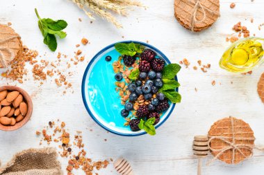 Mavi Spirulina ve Taze Meyve Smoothie Bowl böğürtlen, yaban mersini, granola ve yoğurt ile tepesinde. Kahvaltı. Üst te. Metniniz için boş alan.