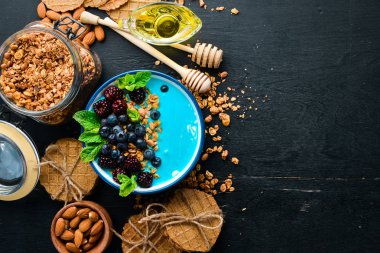 Mavi Spirulina ve Taze Meyve Smoothie Bowl böğürtlen, yaban mersini, granola ve yoğurt ile tepesinde. Kahvaltı. Üst te. Metniniz için boş alan.