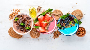 Sağlıklı bir kahvaltı. Yoğurt, taze meyve ve çilek ile renkli meyve smoothies. Üst te. Metniniz için boş alan. Beyaz arka planda.