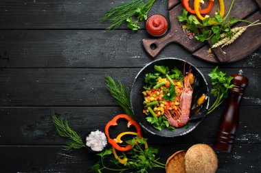 Sebzeli deniz ürünleri. Karides ve midye ile haşlanmış sebze. Siyah bir tabakta. Üst te. Ücretsiz kopyalama alanı.