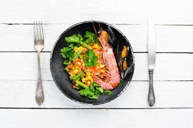 Sebzeli deniz ürünleri. Karides ve midye ile haşlanmış sebze. Siyah bir tabakta. Üst te. Ücretsiz kopyalama alanı.