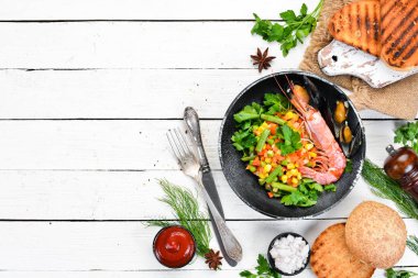 Sebzeli deniz ürünleri. Karides ve midye ile haşlanmış sebze. Siyah bir tabakta. Üst te. Ücretsiz kopyalama alanı.