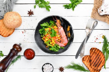 Sebzeli deniz ürünleri. Karides ve midye ile haşlanmış sebze. Siyah bir tabakta. Üst te. Ücretsiz kopyalama alanı.