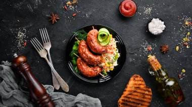 Pirinçli fırında sosis. Siyah bir tabakta. Üst te. Ücretsiz kopyalama alanı.