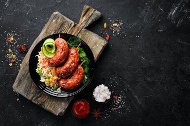 Pirinçli fırında sosis. Siyah bir tabakta. Üst te. Ücretsiz kopyalama alanı.