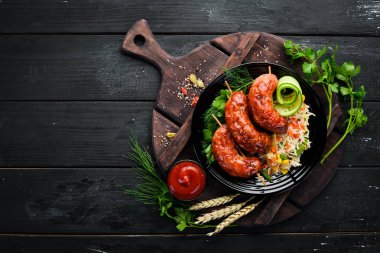 Pirinçli fırında sosis. Siyah bir tabakta. Üst te. Ücretsiz kopyalama alanı.