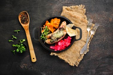 Fırında sosis, tatlı patates ve lahana. Tabakta. Üst te. Metniniz için boş alan. Rustik stil.