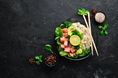 Somon, avokado ve ıspanaklı pilav. Ahşap arka plan üst görünümünde siyah bir tabak ta. Metniniz için boş alan. Düz yatıyordu