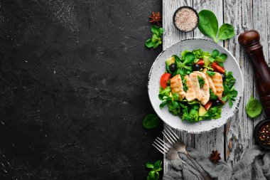 Tavuk fileto, zeytin, domates ve avokado ile salata ahşap bir arka plan üst görünümü üzerinde bir tabakta. Metniniz için boş alan. Düz yatıyordu