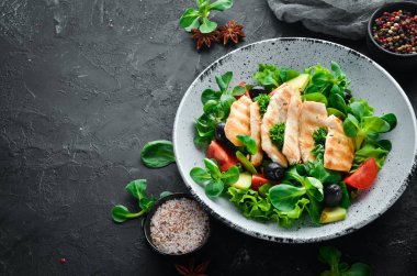 Tavuk fileto, zeytin, domates ve avokado ile salata ahşap bir arka plan üst görünümü üzerinde bir tabakta. Metniniz için boş alan. Düz yatıyordu