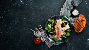 Deniz ürünleri yle pirinç. Karides ve midye ile Risotto. Siyah bir tabakta. Üst te. Ücretsiz kopyalama alanı.