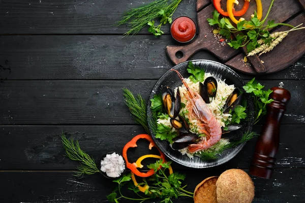 米饭和海鲜 里索托与虾和贝类 在一块黑盘子里顶部视图 免费复制空间 — 图库照片