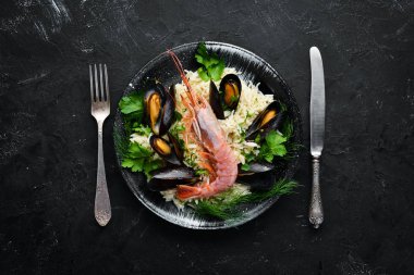 Deniz ürünleri yle pirinç. Karides ve midye ile Risotto. Siyah bir tabakta. Üst te. Ücretsiz kopyalama alanı.