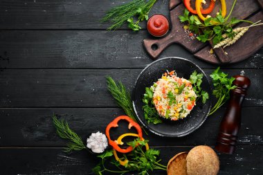 Haşlanmış pirinç ve sebze. Risotto Siyah bir tabakta. Üst te. Ücretsiz kopyalama alanı.