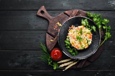 Haşlanmış pirinç ve sebze. Risotto Siyah bir tabakta. Üst te. Ücretsiz kopyalama alanı.