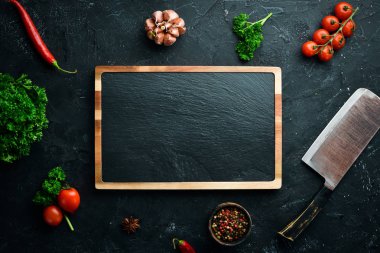 Mutfak tahtası ve baharatlar. Siyah taş arka plan üzerine afiş. Üst te. Metniniz için boş alan.