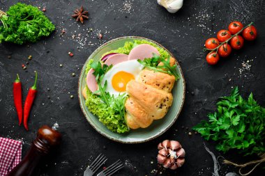 Kızarmış yumurta ve sosis, domates ve soğan ile kruvasan sandviç. Üst te. Metniniz için boş alan.