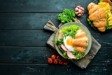 Kızarmış yumurta ve sosis, domates ve soğan ile kruvasan sandviç. Üst te. Metniniz için boş alan.