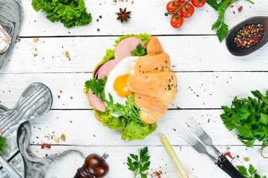 Kızarmış yumurta ve sosis, domates ve soğan ile kruvasan sandviç. Üst te. Metniniz için boş alan.