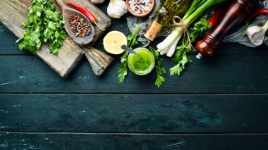 Chimichurri sosu için Malzemeler: taze maydanoz, soğan, sarımsak, zeytinyağı, limon. Siyah bir arka plan üzerinde. Üst te. metniniz için boş alan.