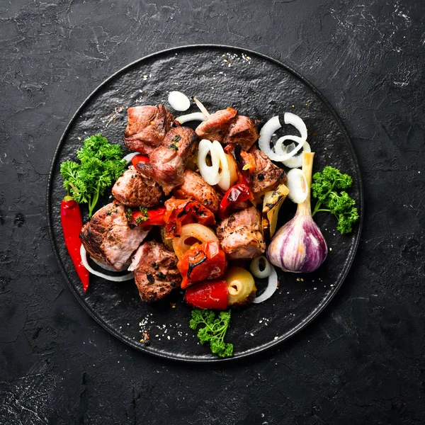 Kebab in a plate. Baked meat with onions and tomatoes. Barbecue. Top view. Free space for your text. Rustic style.