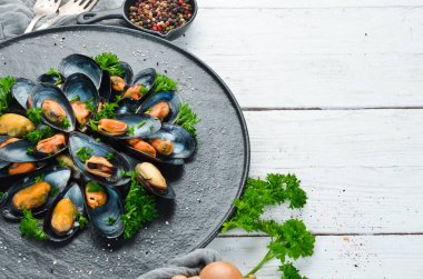 Siyah bir tabakta maydanoz ve baharat ile haşlanmış midye. Üst te. Metniniz için boş alan.