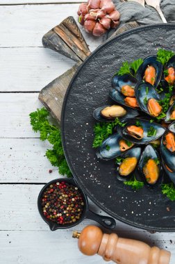 Siyah bir tabakta maydanoz ve baharat ile haşlanmış midye. Üst te. Metniniz için boş alan.